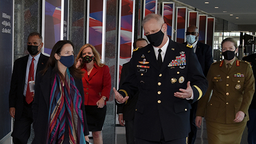 An image of Director Berrier with a group of people, walking in a hall